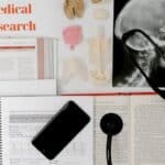 Flat lay of medical research materials with a stethoscope and anatomical models